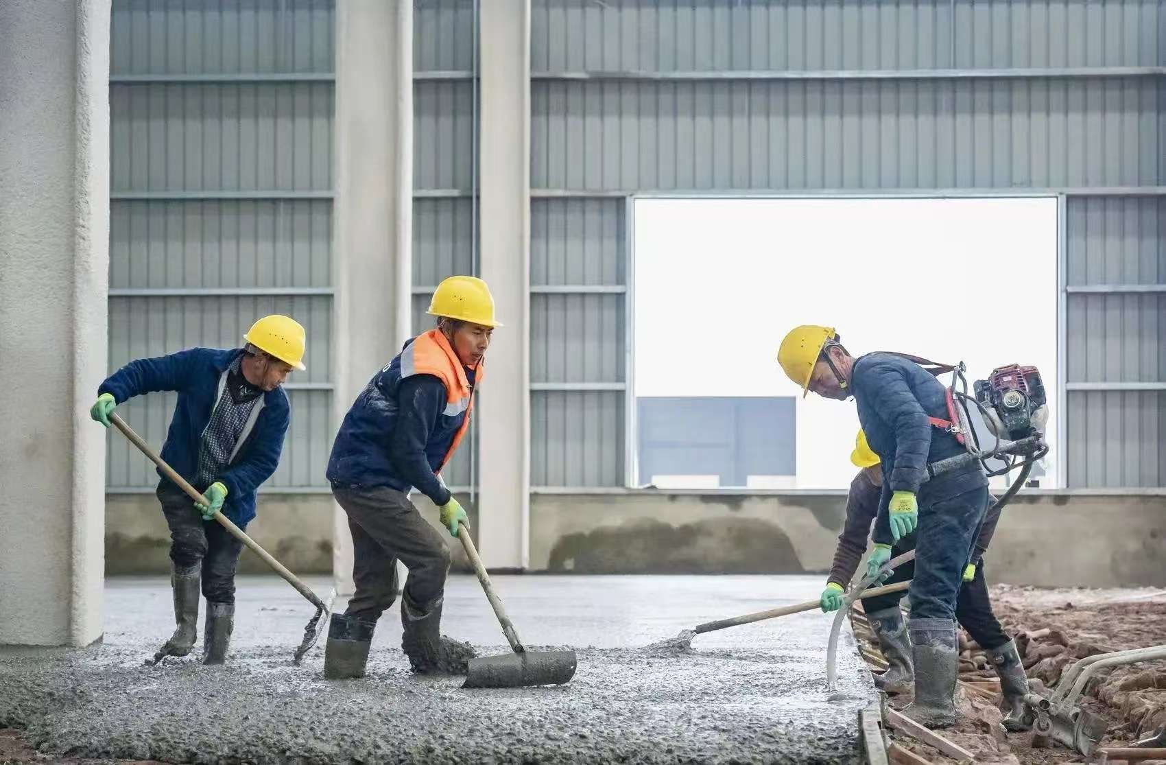 地坪工程施工现场：工人正在进行混凝土地面摊铺与找平作业